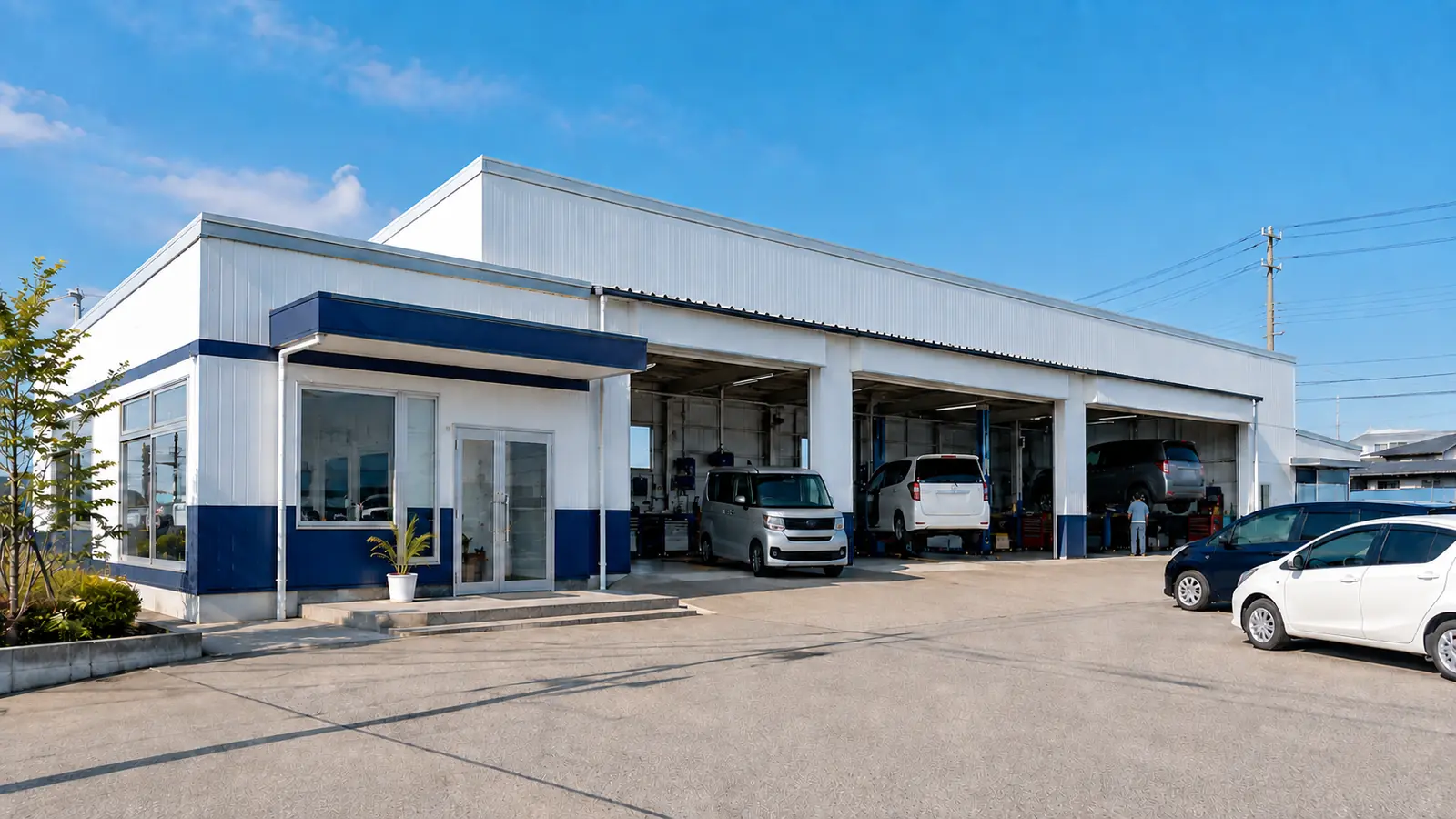 青空の下に建つ地域の自動車整備工場